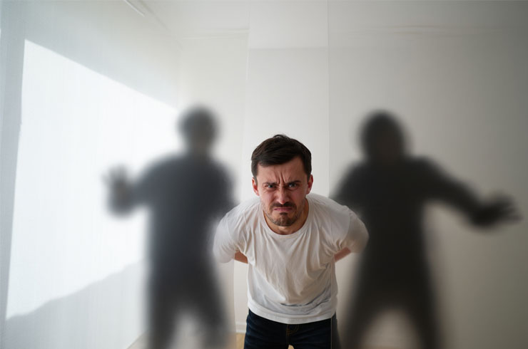 Мужчину за руки держат тени